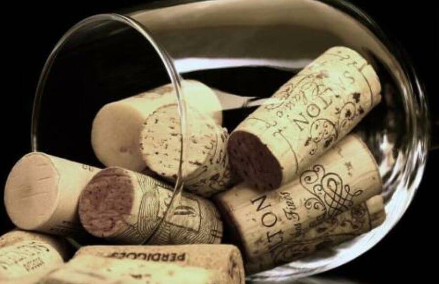 representación de origen del vino con una copa llena de corchos